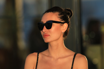 Fototapeta na wymiar portrait of a beautiful brunette girl in sunglasses in a black dress in summer