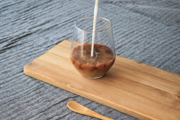 Latte coffee and wooden spoon standing on wood, on gray cover, isolated background