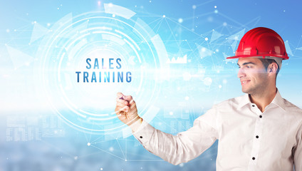 Handsome businessman with helmet drawing SALES TRAINING inscription, contruction business concept