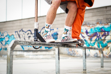 Close-up of a young boy on a scooter. He is going to jump on the ramp and do tricks. 