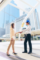 Civil Construction engineer teams shaking hands together wear work helmets worker on construction site. Foreman industry project working engineer teamwork. Two asian engineer team shake hands together