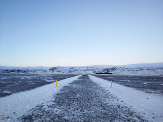 Winter landscape, deserted walking road through a field to the beach in iceland. Huge open space, the road is marked with yellow pillars to avoid getting lost