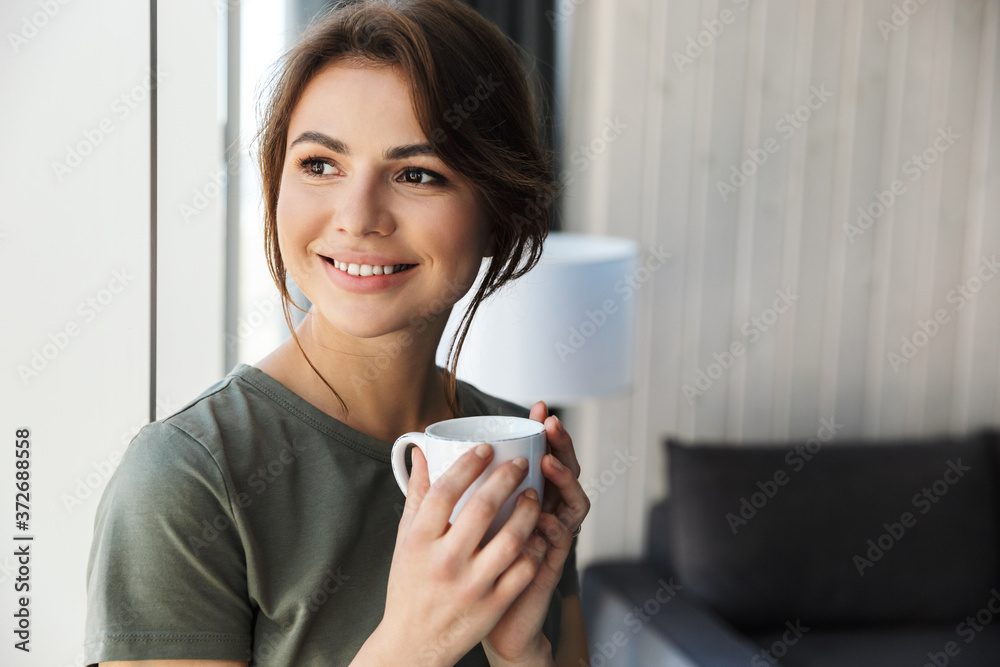 Poster Attractive smiling young woman holding coffee cup