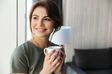 Attractive smiling young woman holding coffee cup