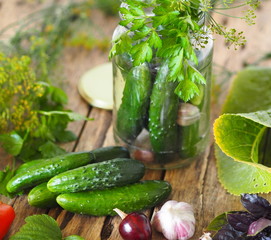 We canning cucumbers for the winter.Homemade canned food with cucumbers in glass jars on a wooden background with fresh cucumbers and ingredients for pickling.