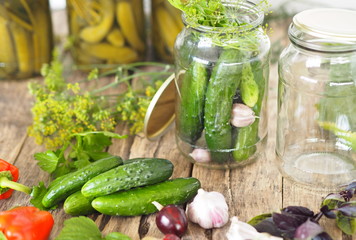 Home remedies for future use.Fresh and pickled cucumbers, homemade canned food with cucumbers in glass jars on a wooden background.