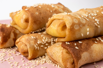 Pancakes homemade with sesame seeds on a pink plate. Delicious sweet breakfast with sugar.
