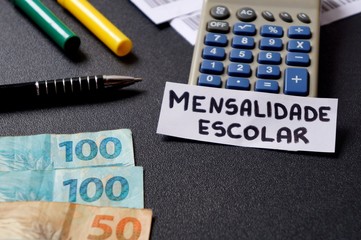 Calculator, Brazilian Real banknotes, pen and mensalidade escolar (tuition) inscription. Concept of school tuition fees in Brazil.