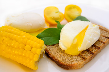 poached egg on a plate with croutons, tomato and corn	
