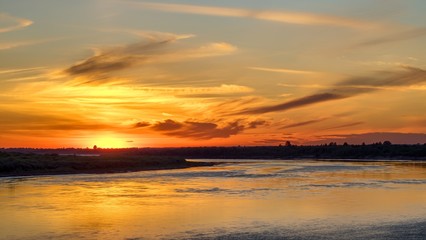 Obraz na płótnie Canvas Beautiful orange sunset over big river.