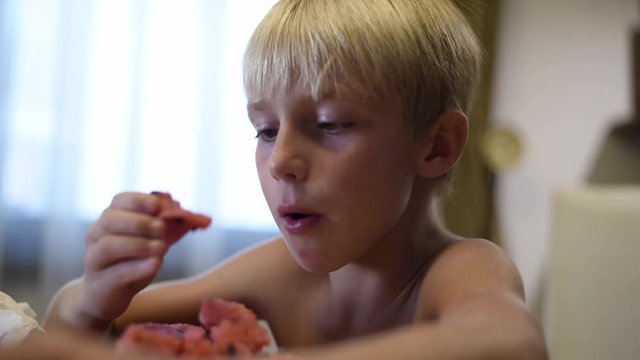 Kid eating watermelon and spitting the seeds, handled footage.