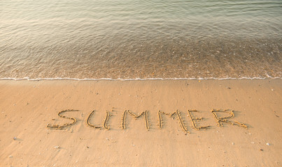 Handwritten summer on sand on the see beach. Word Summer. Vacation and holiday concept
