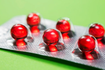 Metal drug blister with red medicine capsules.