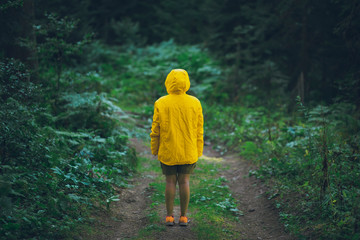A portrait of jogger woman in a forest with yellow jacket in moody folk green tones.