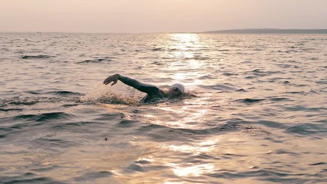 A man is swimming breaststroke through the sea