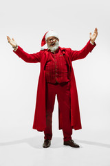Greeting man. Modern stylish Santa Claus in red fashionable suit isolated on white background. Looks like a rockstar. New Year and Christmas eve, celebration, holidays, winter's mood, fashion.
