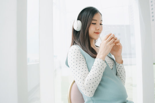 Healthy mom listen to music holding a cup of milk.