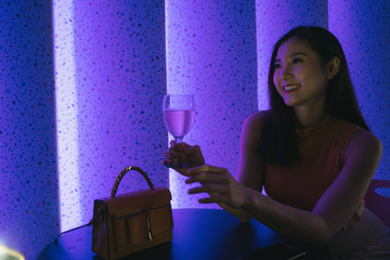 Asian thai woman holding glass of champagne wine in nightclub.