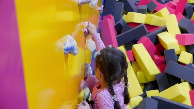 Little girl try to climp to the climbing wall and falls to pool