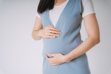 Beautiful pregnant asian woman holding belly isolate over white background.