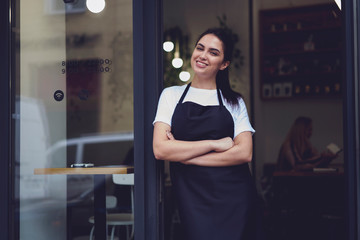 Female owner of restaurant with smile standing near cafe door entrance