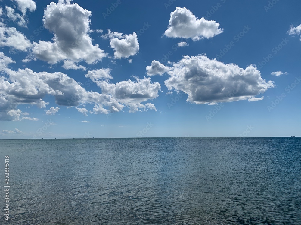 Wall mural blue beautiful sky and white clouds over the ocean. clear weather, beautiful contrast against the ba