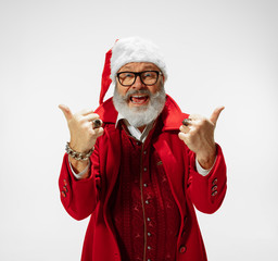 Fototapeta na wymiar Thumbs up, cool. Modern stylish Santa Claus in red fashionable suit isolated on white background. Looks like a rockstar. New Year and Christmas eve, celebration, holidays, winter's mood, fashion.