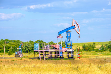 Fototapeta na wymiar Rocking chair for oil extraction in the arid steppe on a sunny day against the blue sky. Industrial oil production. High quality photo