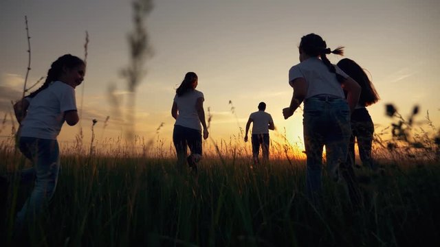 Happy family. A group of children runs in the Park at sunset. Big family together mom dad daughter and son have fun in the summer. Happy, laughing, healthy children.