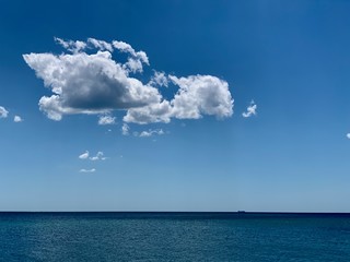Obraz premium Blue beautiful sky and white clouds over the ocean. Clear weather, beautiful contrast against the background of clear sky and water. Between sea and sky.