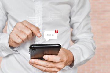Businessman hand using mobile phone typing, with chat icons. Social media and technology concept.