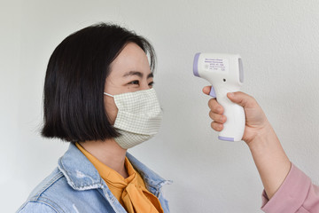 Hand holding infrared forehead thermometer to check body temperature. Concept of protect from...