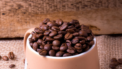 Mug full of coffee beans on the background of the bag,large Plenum