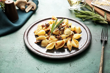 Plate with tasty conchiglie pasta on color background