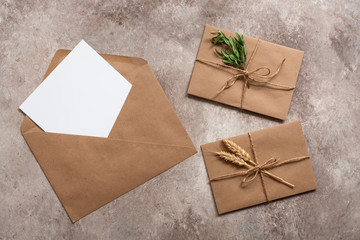 Blank card in craft envelope and vintage letters on on a beige grunge background. Modern minimal mockup. Top view, flat lay.