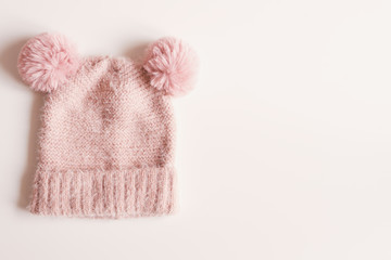 Fototapeta na wymiar Handmade knitted hat with funny pompoms on white background, top view, copy space. Warm clothing