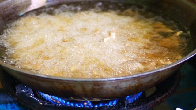 The process of frying tempeh in a wok pan in the kitchen for dry tempeh (kering tempe). 