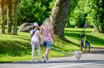 Obraz premium Mother with daughter and dog walking in the city Park 