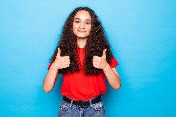 Fototapeta na wymiar Smiling pretty young woman showing thumbs up on the blue background