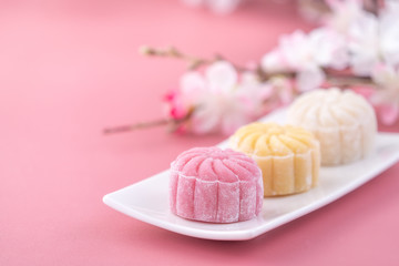 Obraz na płótnie Canvas Colorful snow skin moon cake, sweet snowy mooncake, traditional savory dessert for Mid-Autumn Festival on pastel pale pink background, close up, lifestyle.