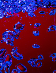 Close up view of the cold and fresh cola with bright bubbles in neon light. Texture of cooling summer's drink with macro bubbles on glass. Fizzing or floating up to top of surface, splashing fluid.