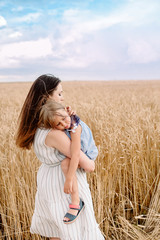 Young mother hugging her sad little daughter. Sad daughter in mother's arms in wheat field