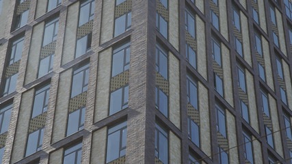 Fototapeta premium Establishing exterior brick apartment loft building in one of the districts urban city. Windows and balconies of Apartment building in Residental Area
