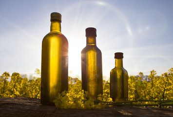 Set glass bottle of rapeseeds oil and blooming yellow canola
