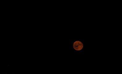 Plane flying by a red moon