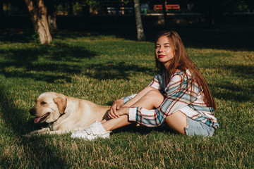 Portrait of beautiful young woman with dog  which sits on green grass