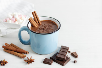 Spicy hot chocolate with cinnamon and star anise in enamel blue mug on white background.