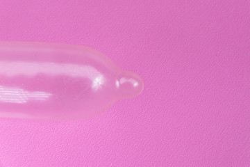 Latex condom on pink background