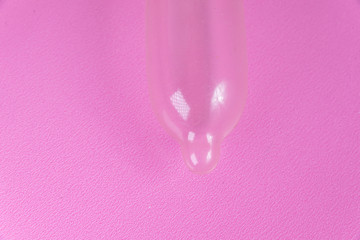 Latex condom on pink background