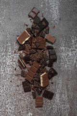 Pile of chopped, milled dark and milky chocolate slices and shavings top view.